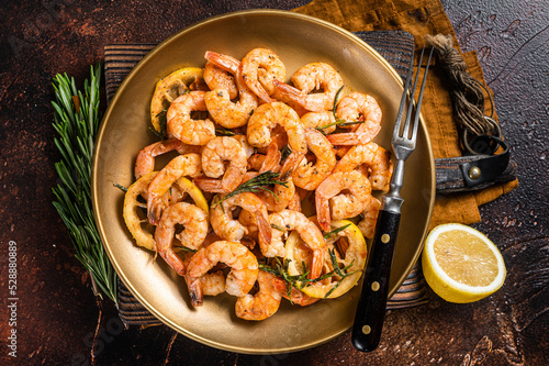 Spicy garlic chilli Prawns Shrimps with lemon and rosemary on a plate. Dark background. Top view