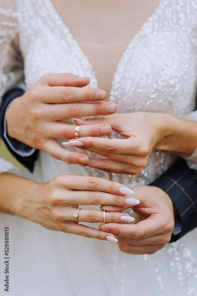 Wedding close-up portrait of the hands and fingers with golden rings of the bride and groom at an outdoor ceremony. Festive photo of newlyweds, idea. Wedding close-up portrait of the hands and fingers with golden rings of the bride and groom at an outdoor ceremony. Festive photo of newlyweds, idea.