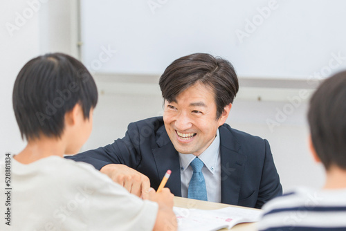小学生に勉強を教える笑顔の塾講師・先生（日本人男性） 