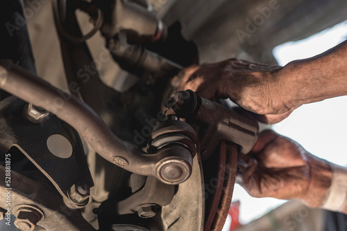 A mechanic tightens the bolts of the brake caliper with his bare hands. At an automotive repair shop. photo