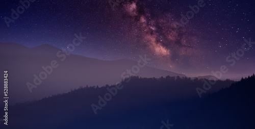 Night in the autumn mountains. Starry sky, yellow leafy trees and fog.