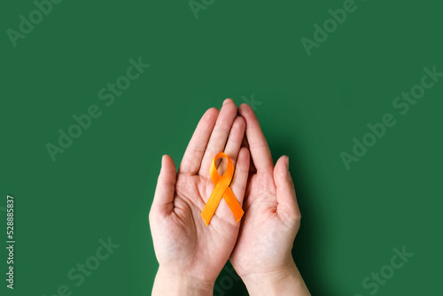 World COPD day. Medical campaign against Chronic Obstructive Pulmonary Disease in november. World Multiple Sclerosis day. Woman's hands hold an orange ribbon