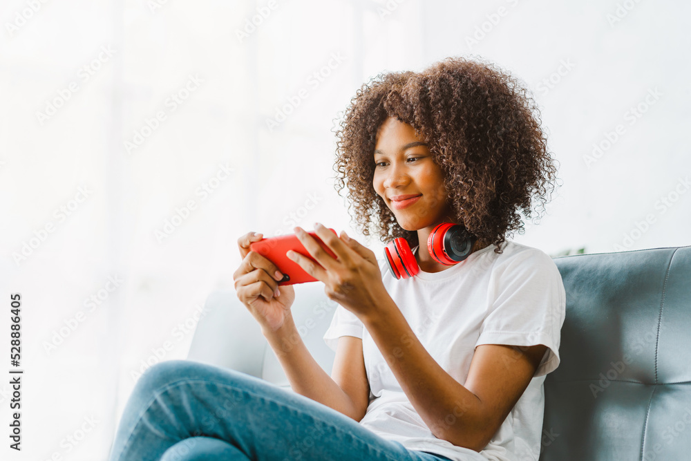 Excited cheerful gen Z female using mobile phone getting surprising good news while playing mobile game on sofa. - obrazy, fototapety, plakaty 