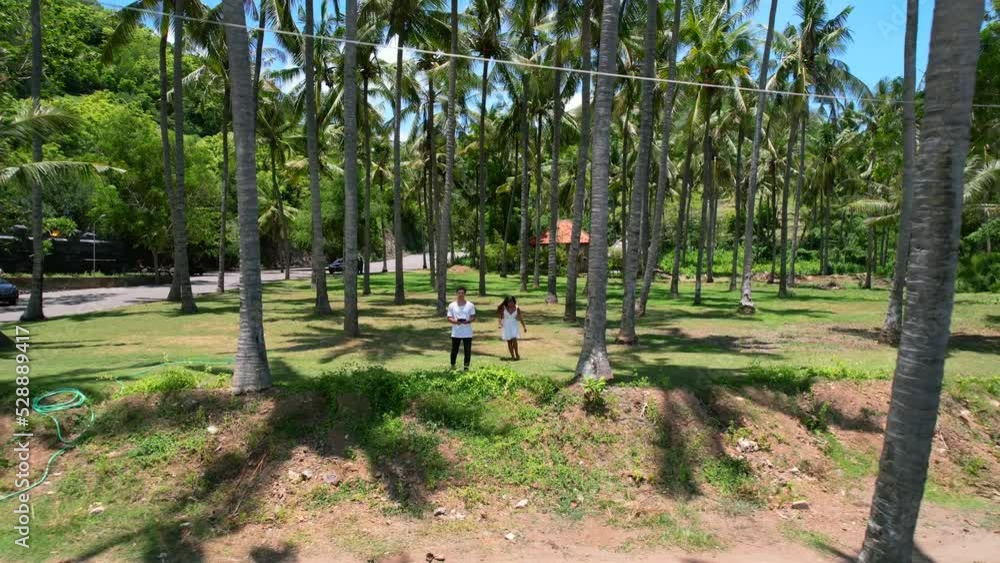 young couple running through tropical coconut tree field at Pantai Prasi in bali on sunny day, aerial young couple running through tropical coconut tree field at Pantai Prasi in bali on sunny day, aerial