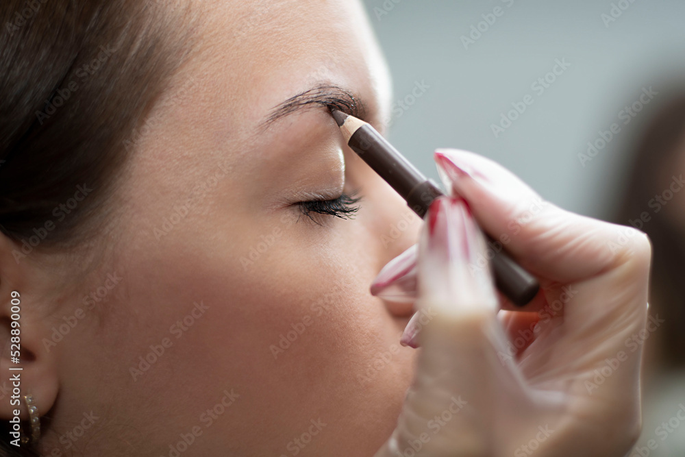 People. Beauty and health. Eyebrow flexing. The make-up artist corrects the eyebrows of a young beautiful Caucasian girl