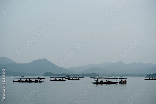 Hangzhou / China - 05.16.2019 : Water tourist trips. People are sailing on a vintage boat in the Chinese style.