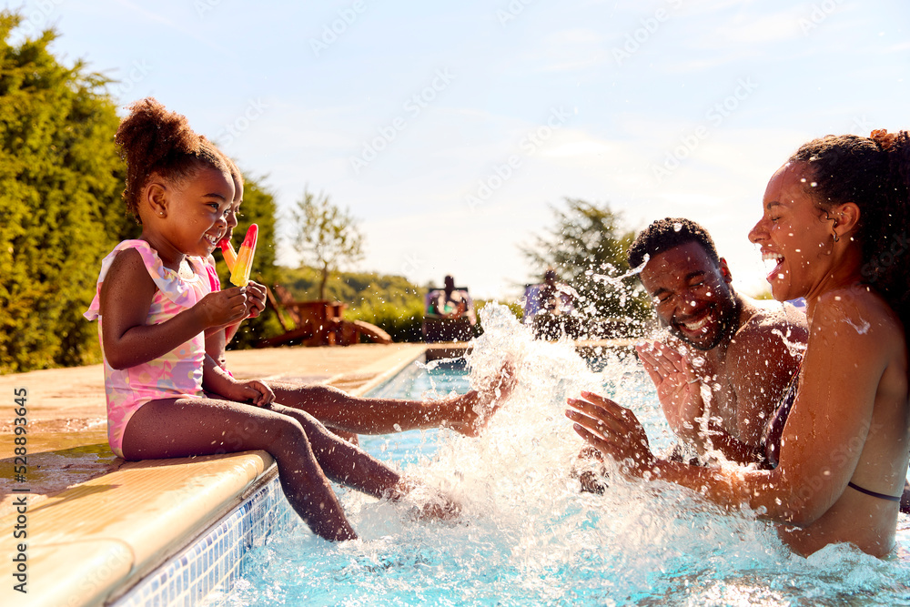 Family On Summer Holiday With Two Girls Eating Ice Lollies By Swimming ...