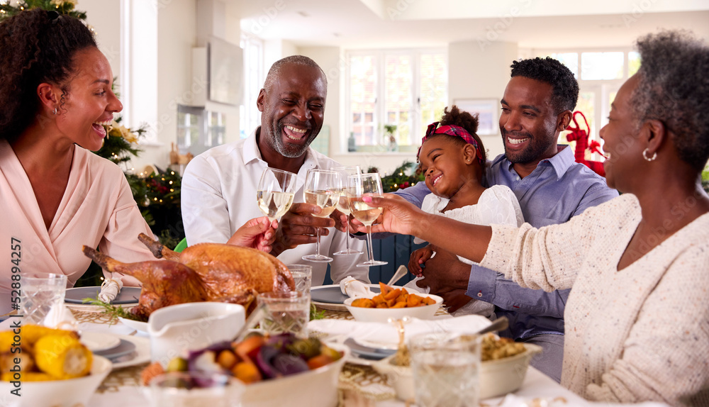 Multi-Generation Family Celebrating Christmas At Home Eating Meal And Making Toast With Wine