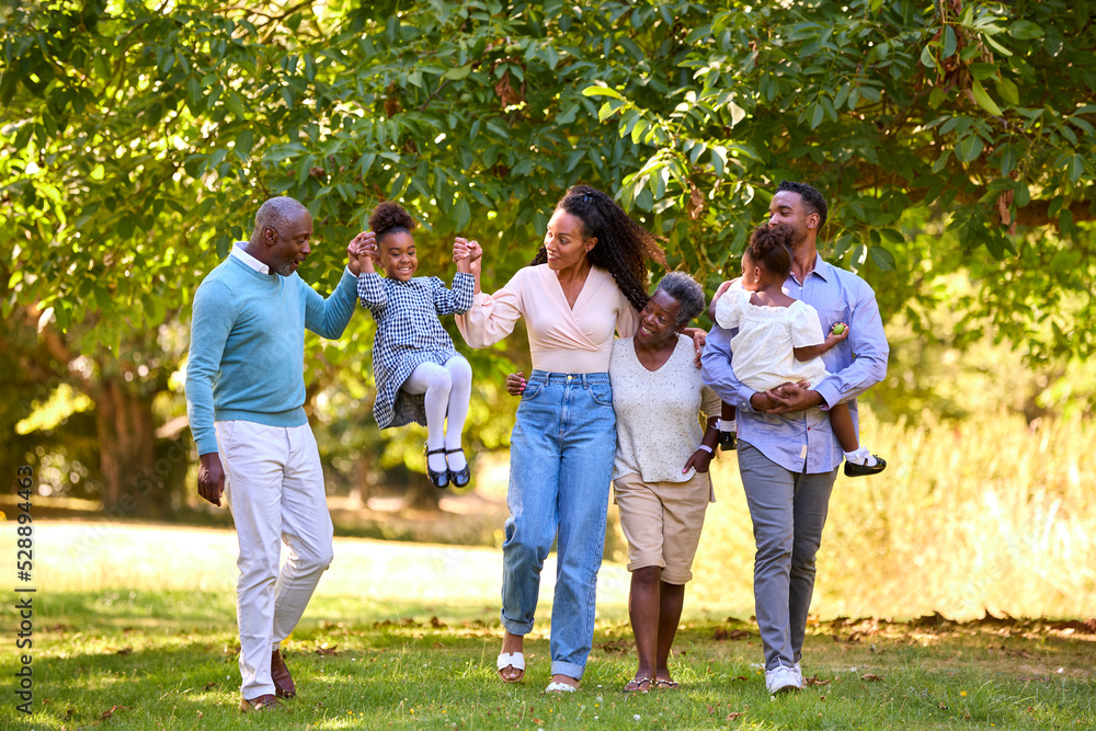 Fototapeta premium Multi-Generation Family Enjoying Walk In Countryside Together Swinging Granddaughter