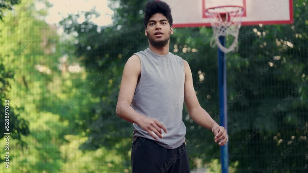 Sportive young man playing street basketball dribbling and throwing ball in hoop Sportive young man playing street basketball dribbling and throwing ball in hoop