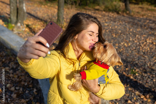 a woman takes a selfie on a smartphone with her small dog yorkshire terrier
