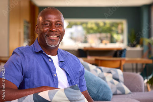 Portrait Of Retired Smiling Senior Man Relaxing On Sofa At Home