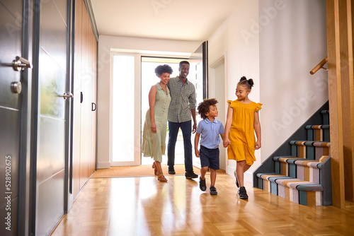 Family Coming Home After Day Out Opening Front Door And Walking Into Hallway