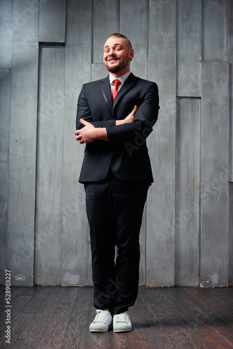 Elegance and fashion. Handsome young man wearing toxedo and tie on wooden background. photo