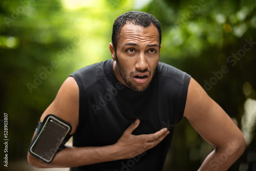 Black sportsman with heart pain, training outdoors photo