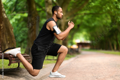 Fototapeta Naklejka Na Ścianę i Meble -  Motivated muscular black man exercising in the park, side view