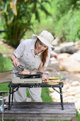 Smiling woman grilled bbq for dinner during camping on summer holiday. Travel, tour adventure on nature and vacation concept