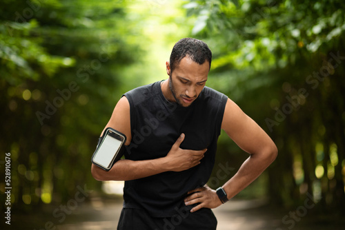 Muscular black man with heart pain, training outdoors
