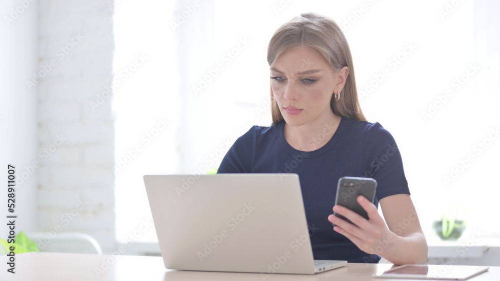 Woman using Smartphone while using Laptop Woman using Smartphone while using Laptop