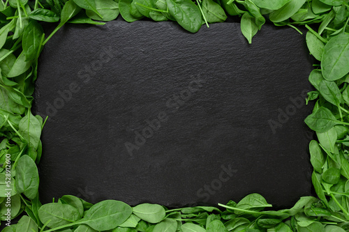 Kitchen table with stone cutting board, decorated with herbs. Presented on the black wooden background with center empty space. Table top view.