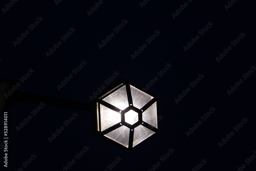 Underside of white street lamp on black background with copy space. Concept for light in darkness, lantern, lamp, alone, solitude, light and dark Underside of white street lamp on black background with copy space. Concept for light in darkness, lantern, lamp, alone, solitude, light and dark