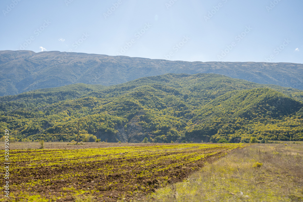Obraz premium plowed field against the background of mountains in Albania. Agricultural landscape