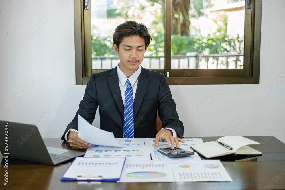 Young Asian businessman financial market analyst sits at their desks and calculate financial graphs showing the results of their investments planning the process of successful business growth Young Asian businessman financial market analyst sits at their desks and calculate financial graphs showing the results of their investments planning the process of successful business growth