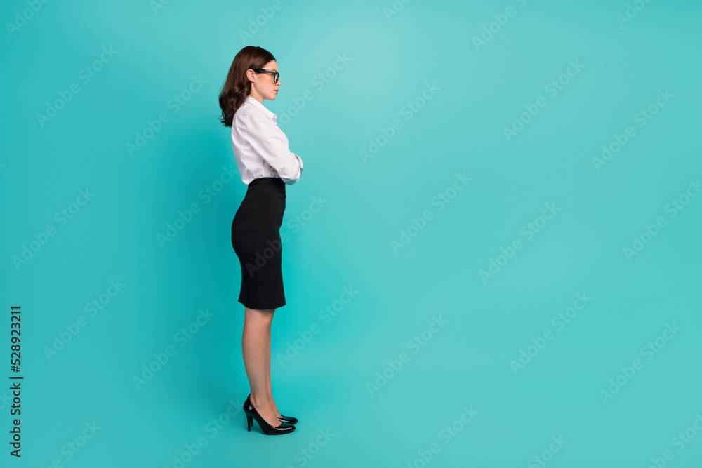 Full length profile side photo of young university professor look empty space cross arms isolated cyan color background Full length profile side photo of young university professor look empty space cross arms isolated cyan color background