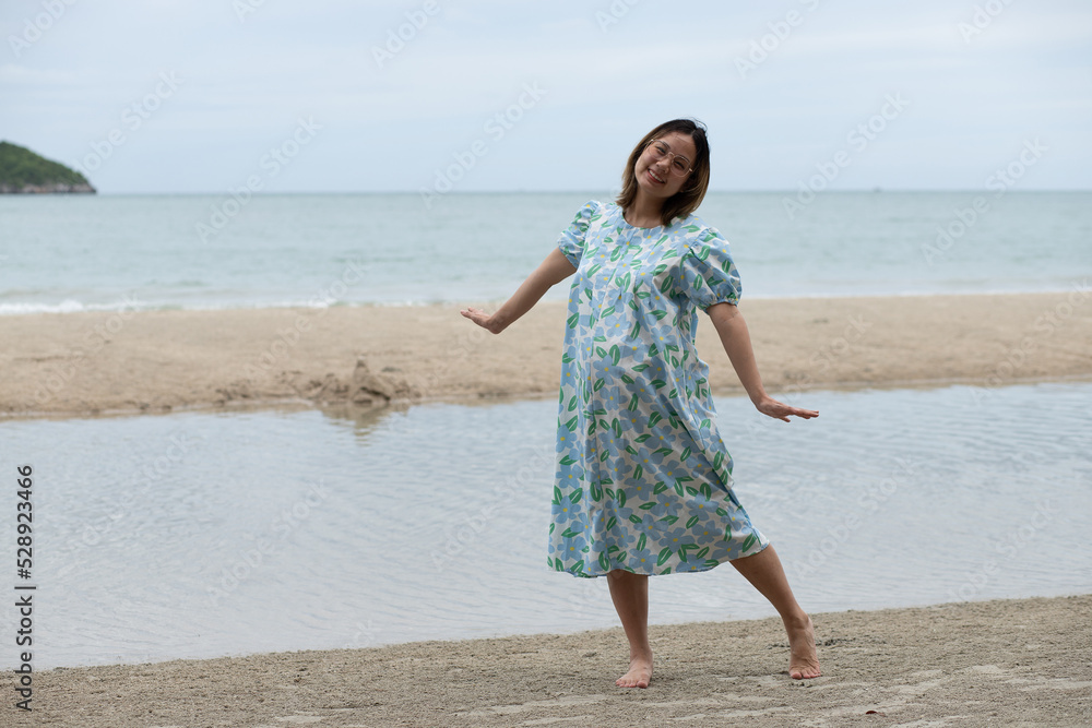 Beautiful young pregnant woman walking on the beach feel peace Beautiful young pregnant woman walking on the beach feel peace