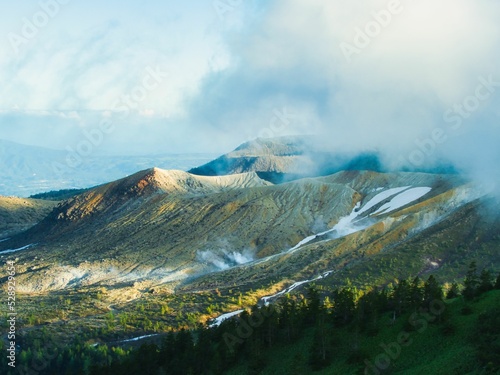 噴煙と残雪を見る山