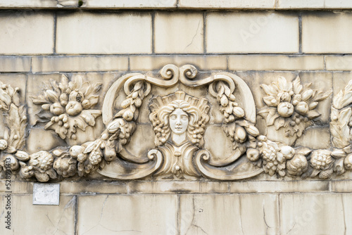 The facade of an old building decorated with a pattern of stucco. Mythical creatures on the facade of an old house.