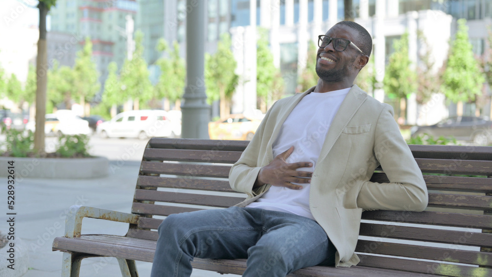 African Man having Back Pain while Sitting on Bench Outdoor African Man having Back Pain while Sitting on Bench Outdoor