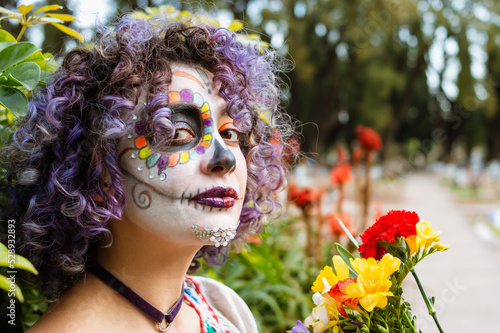 portrait of young woman visiting cemetery with La Calavera Catrina makeup photo
