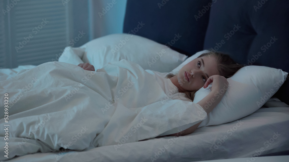 Woman looking away while suffering from insomnia in bedroom at night. Woman looking away while suffering from insomnia in bedroom at night.