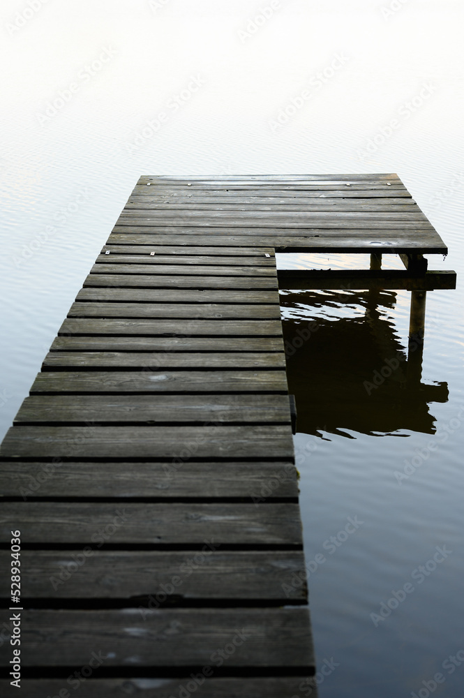 Obraz premium wooden footbridge on lake with reflection on lake in Germany
