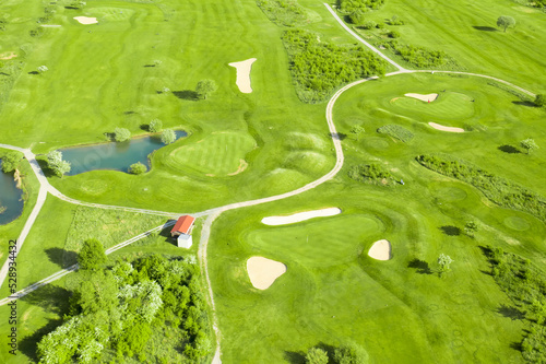 Golf course with sand bunker, green grass and pond, aerial view.