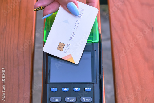 Close-up of a credit card and a payment terminal. Contactless bank card with NFC technology. Payment with the terminal