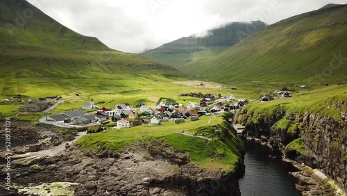 Aerial view of a canyon in Gjogv village in Faroe Islands. Sunny day in summer. Amazing nature. Eysturoy. Faroese canyon. Natural harbour in Gjogv. Tyril and Slaettaratindur in the background. photo