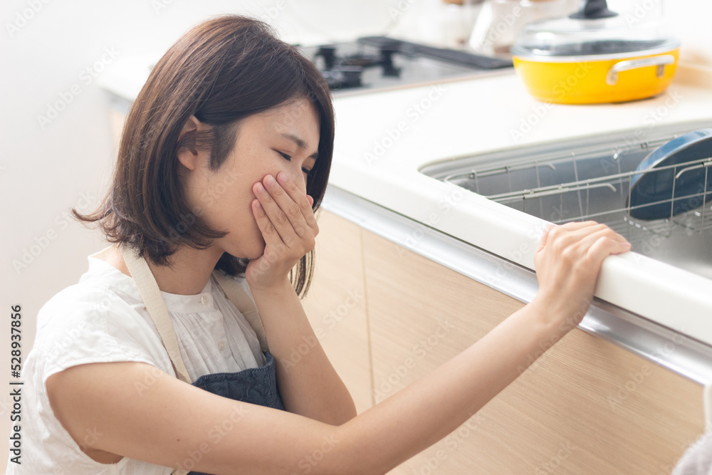 料理中につわりで苦しむ女性 料理中につわりで苦しむ女性