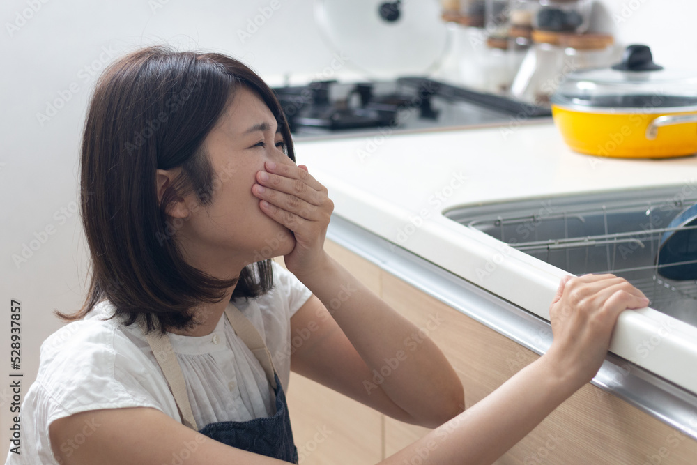 料理中につわりで苦しむ女性 料理中につわりで苦しむ女性