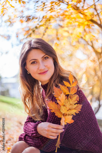 Beautiful woman in burgundy sweater on a background of autumn tree.