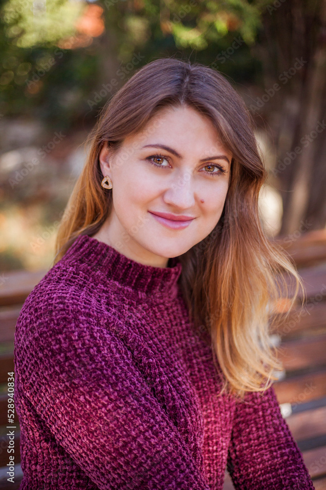 Portrait of beautiful woman in burgundy sweater on a background of autumn tree.
Portrait of beautiful woman in burgundy sweater on a background of autumn tree.