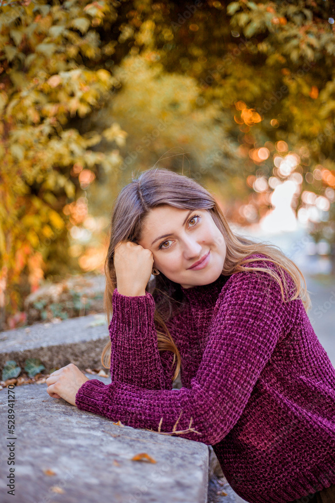 Fototapeta premium Portrait of beautiful woman in burgundy sweater on a background of autumn tree. 