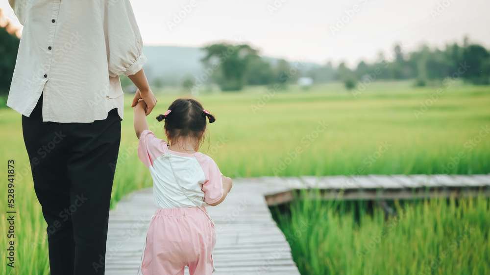 A single mother and cute little daughter sit on the bridge among the green rice fields as the sunset, Protecting and teaching dreams and living in the future when growing up. A single mother and cute little daughter sit on the bridge among the green rice fields as the sunset, Protecting and teaching dreams and living in the future when growing up.