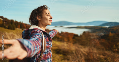 Fotografia Young beautiful hiker woman admiring nature view opening arms into the sky on mo