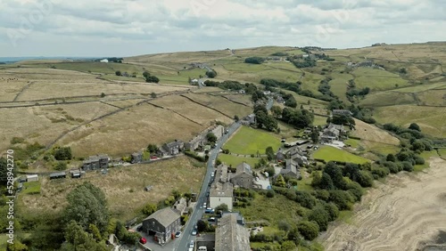 Aerial footage of a industrial rural village with old mill and chimney stack surrounded by fields. Shot at Leeming above Oxenhope and adjacent to Leeming Reservoir. Shot in West Yorkshire England. photo