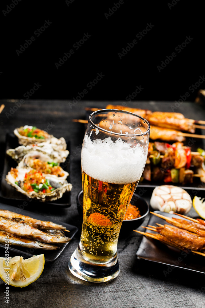 A variety of barbecue dishes and beer are placed on the black wooden background A variety of barbecue dishes and beer are placed on the black wooden background
