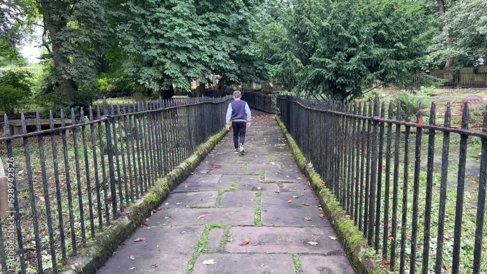 Young Boy walking through the graveyard at St Michael and All Angels Church Graveyard, Haworth, final resting place of the Bronte family. Young Boy walking through the graveyard at St Michael and All Angels Church Graveyard, Haworth, final resting place of the Bronte family.