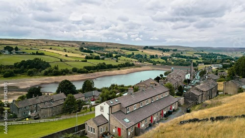 Aerial footage of a rural industrial village with old mill and chimney stack. Shot at Leeming above Oxenhope and adjacent to Leeming Reservoir. Shot in West Yorkshire England during the summer months photo