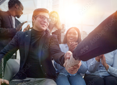 employees congratulating their colleague at a work meeting. photo